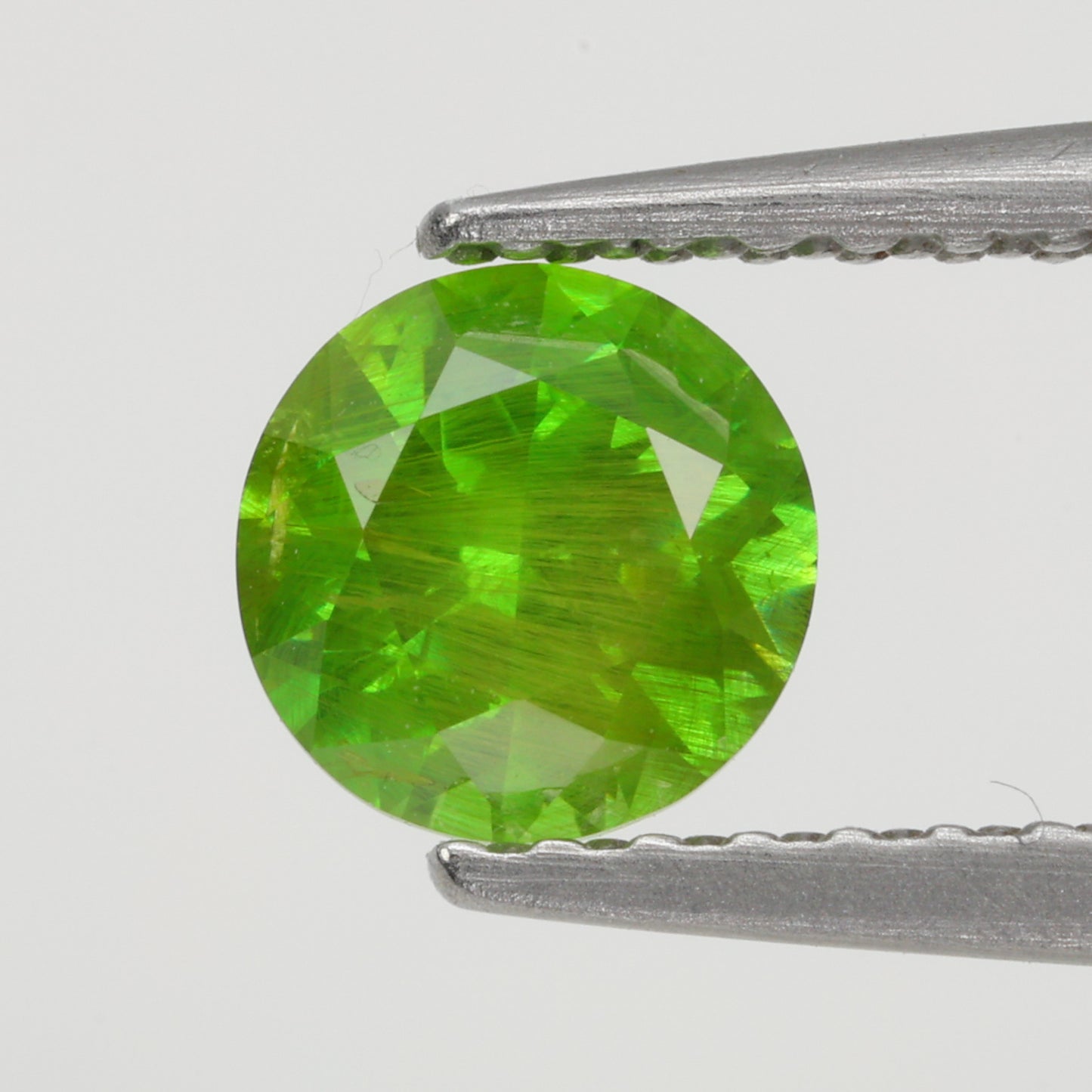 0.62 ct, Faceted Russian demantoid garnet with horsetail byssolite inclusions